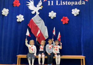 dzieci w strojach galowych pozują z flagami do zdjęcia